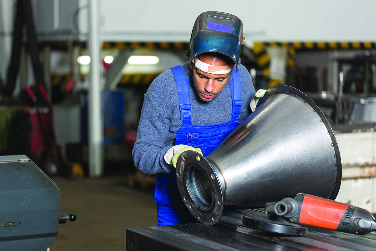 Welder inspecting metal piece for quality control