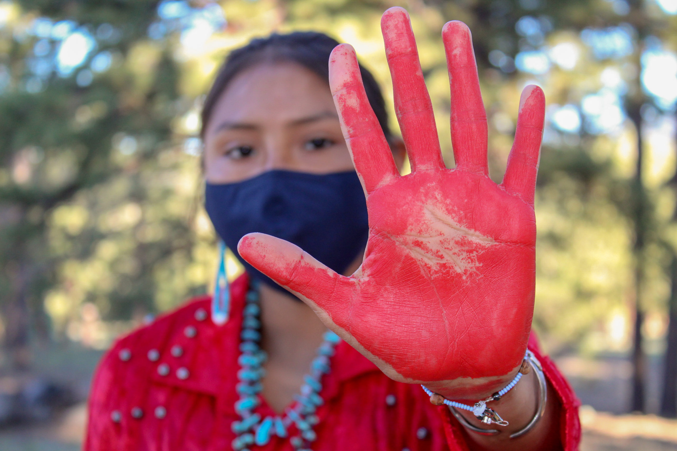 Indigenous woman holding out painted hand as a symbol for awareness