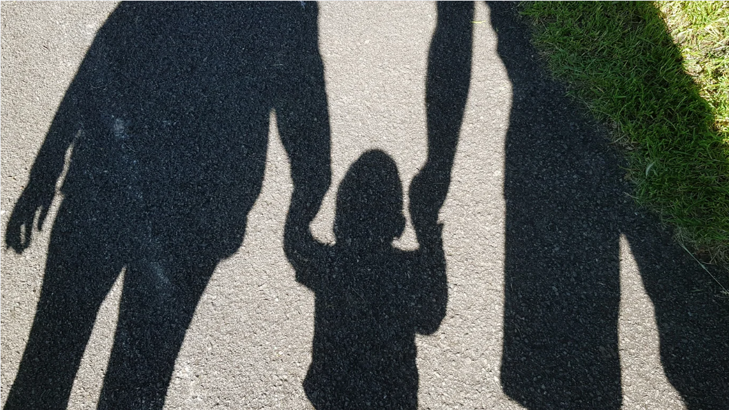 shadows of two adults holding hands with a child