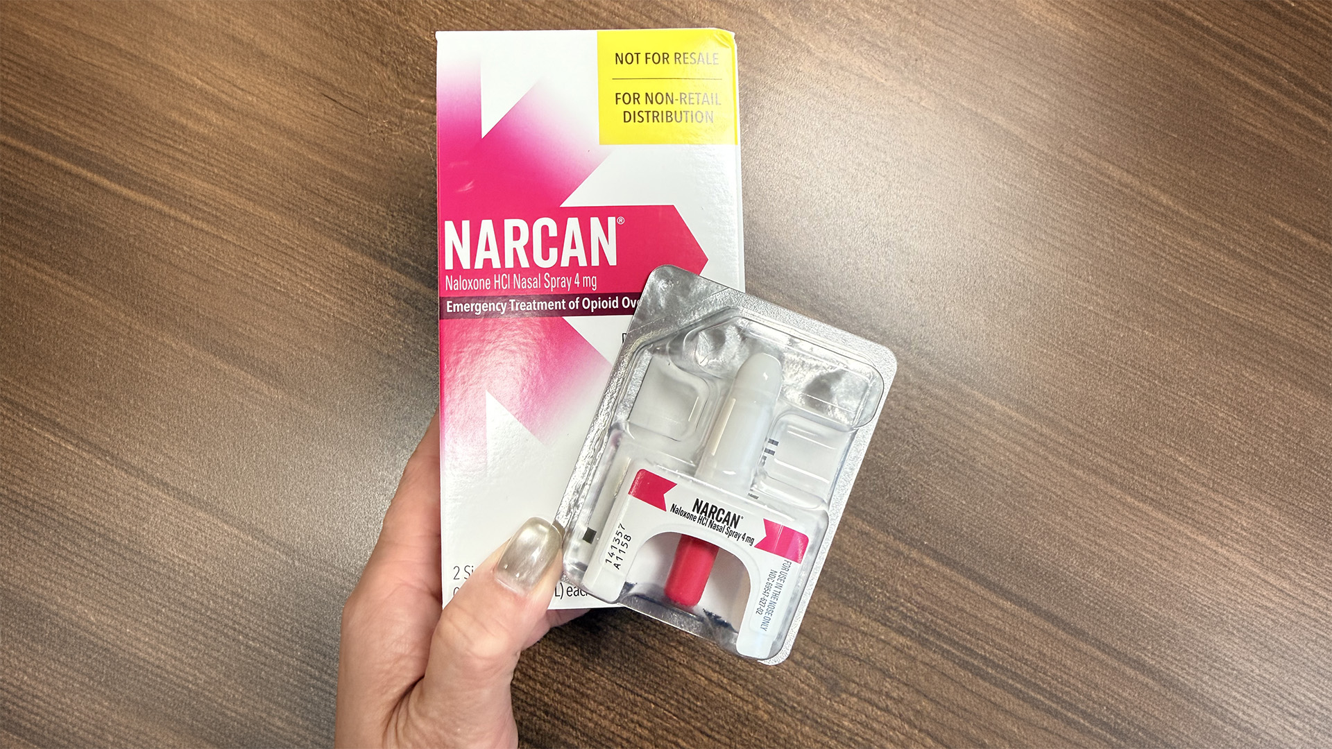 A hand holding a box of naloxone